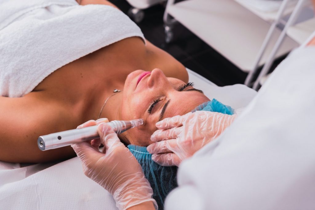 Cosmetologist making mesotherapy treatment with dermapen on face of woman in the aesthetic center